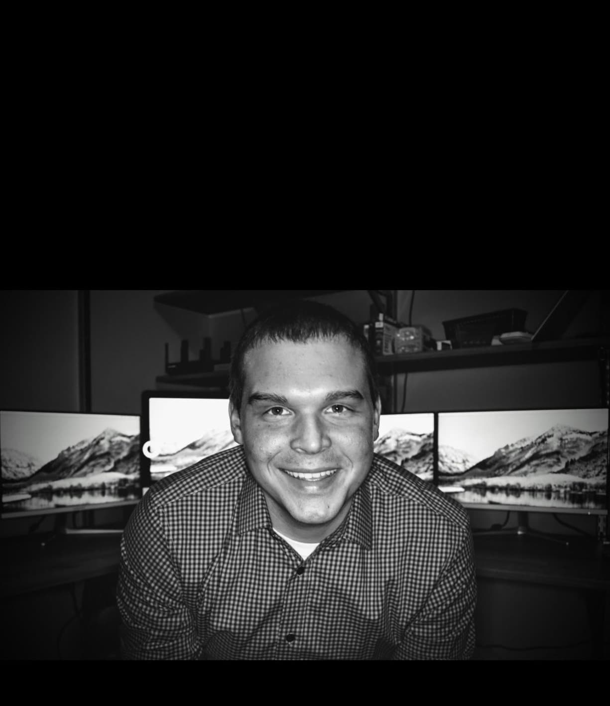 Frank Foust smiling at a desk with several computer monitors